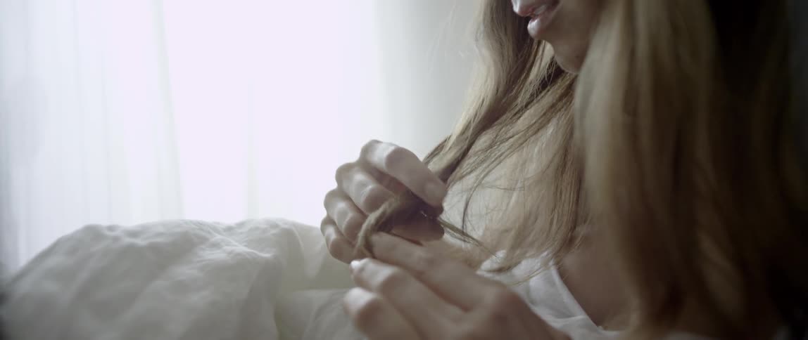 A woman fiddles with her hair in bed