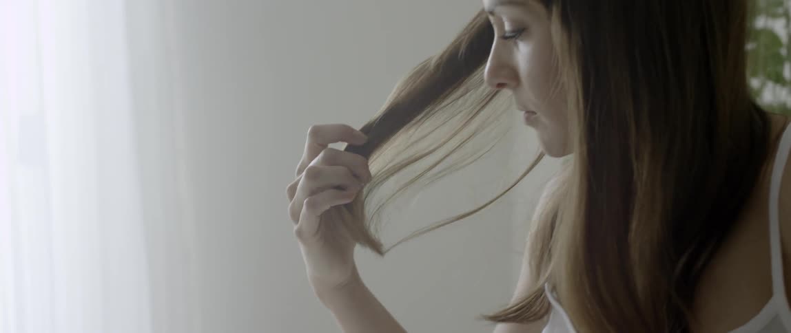 A woman grabs and feels her hair