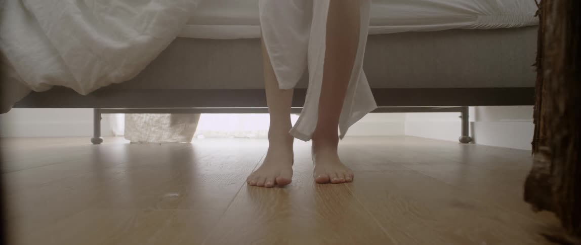 A woman's feet hit the floor as she gets out of bed