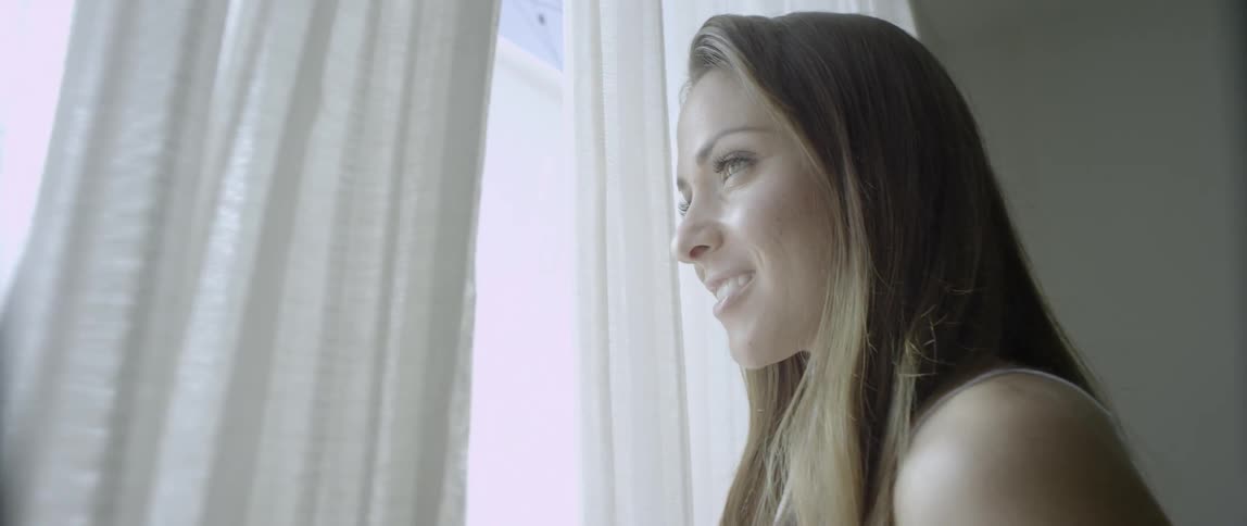 Woman with long blond hair looks out the window