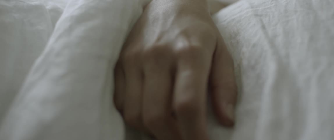 A woman's arm is resting over a bed covering as she sleeps