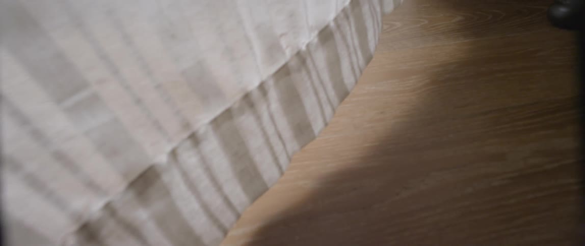The hem of a curtain blows in the breeze
