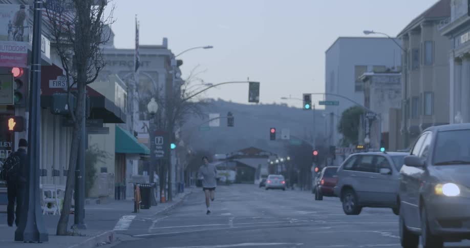 A person jogs down a city street in the morning