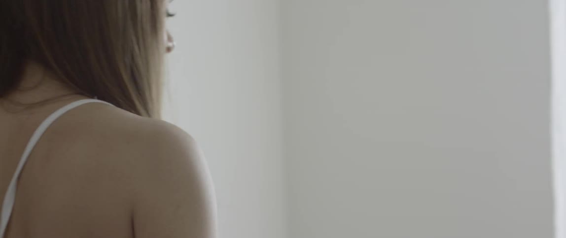 A woman is walking to the window in her bedroom