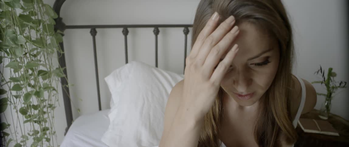 A girl wakes up in her bed and looks towards the window