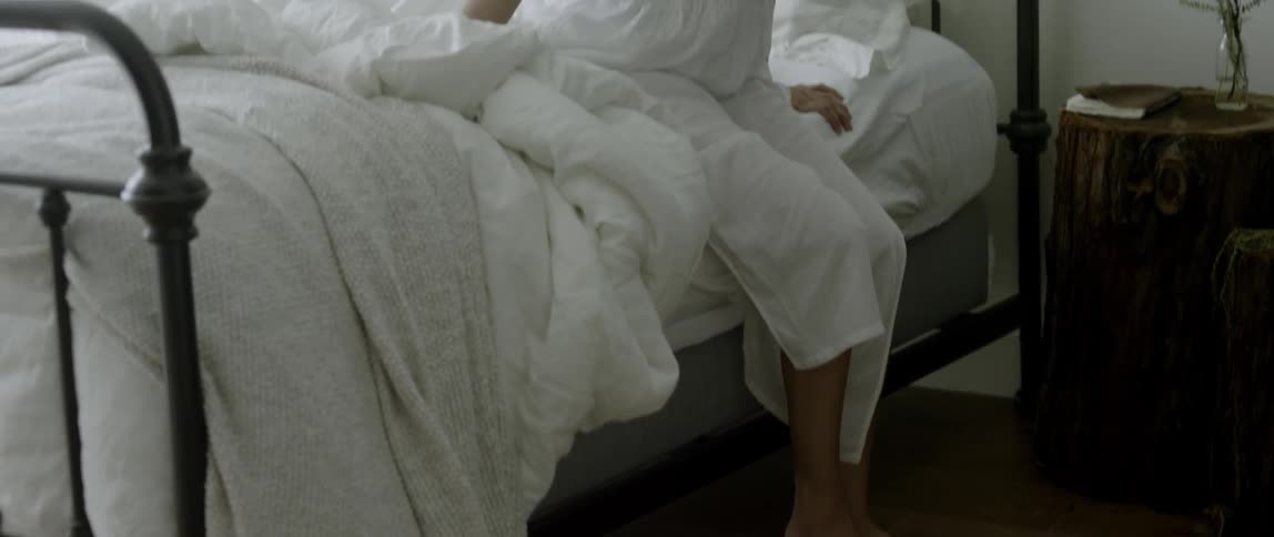 A woman stands up from bed