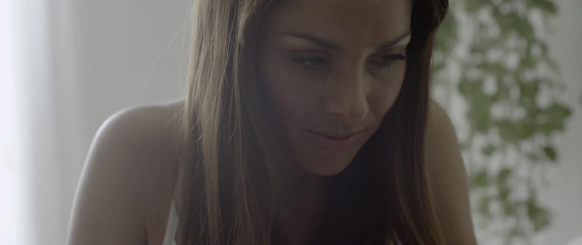 A woman getting up from sleep reaches toward a nightstand