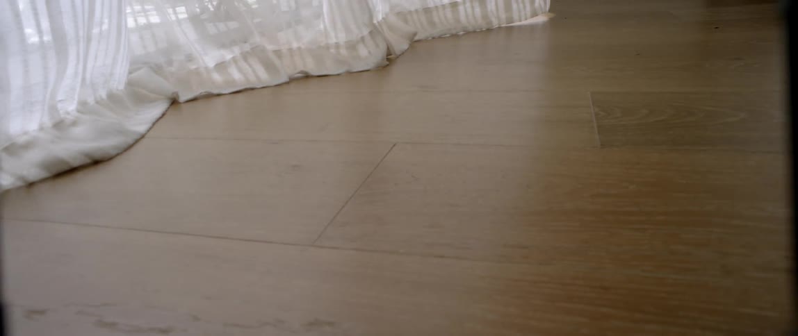 Curtains blow gently in a breeze over a wood floor