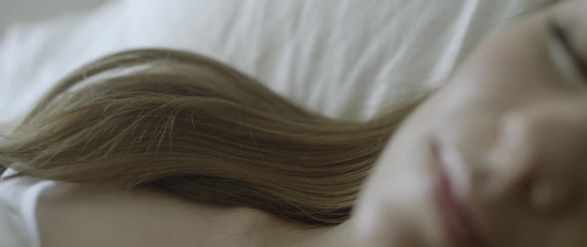 A blond woman lays in bed
