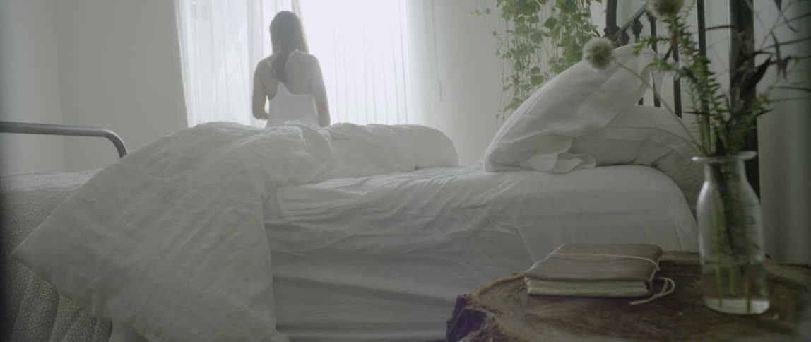 A woman walks out of an open window in a bedroom