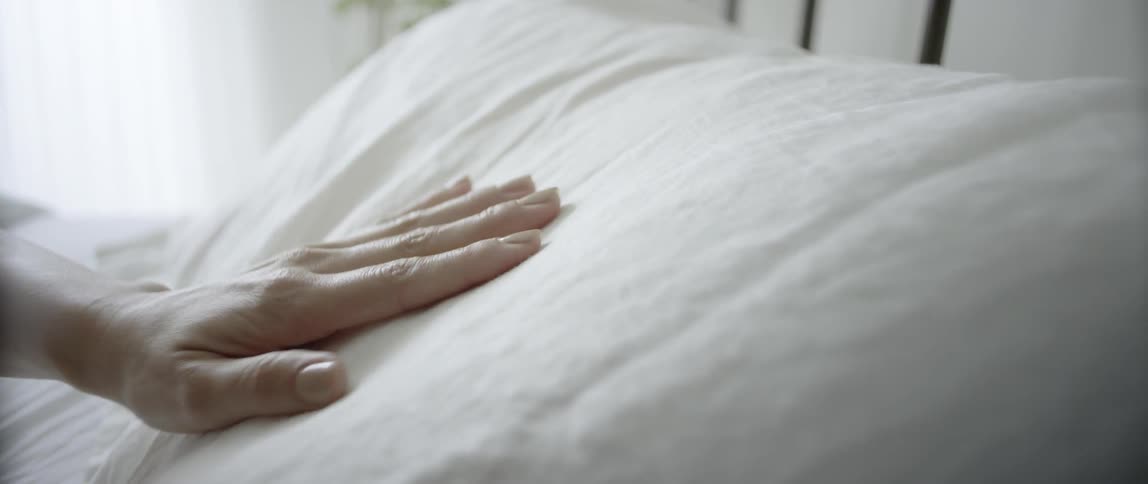 A woman touches and feels a bed pillow