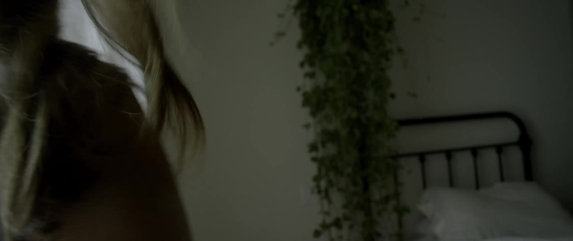A woman's hair blows in a breeze near a window