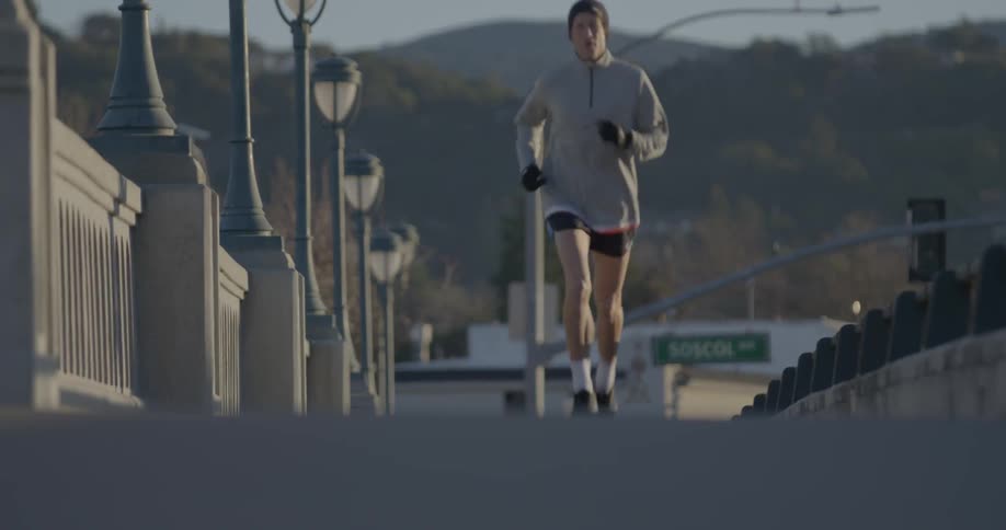 A man is jogging over a bridge