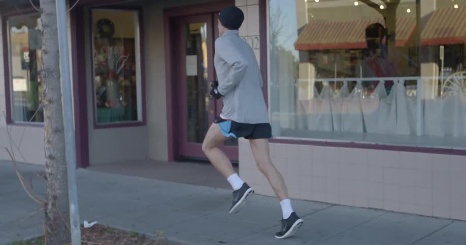A man jogs down a sidewalk in a city