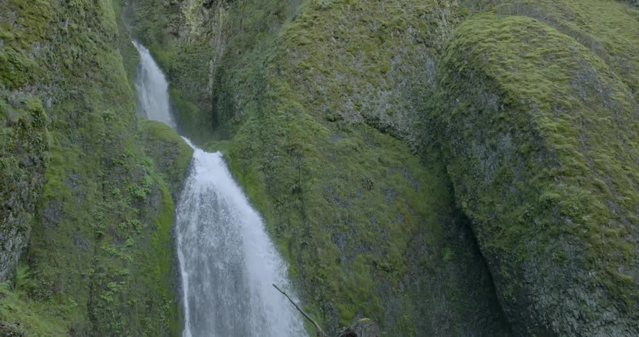 A waterfall flows near a grassy mountainside
