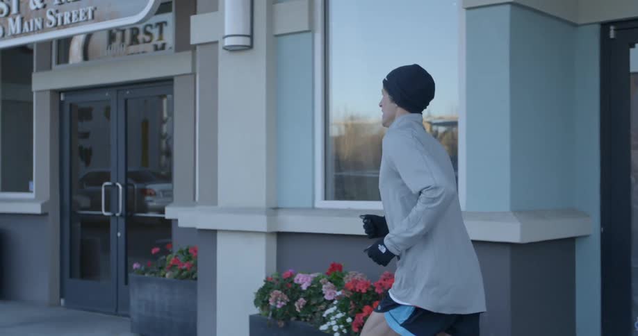A man jogs on a sidewalk in the morning