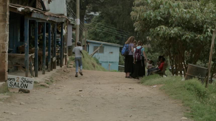 People talk to each other on a dirt road in a village