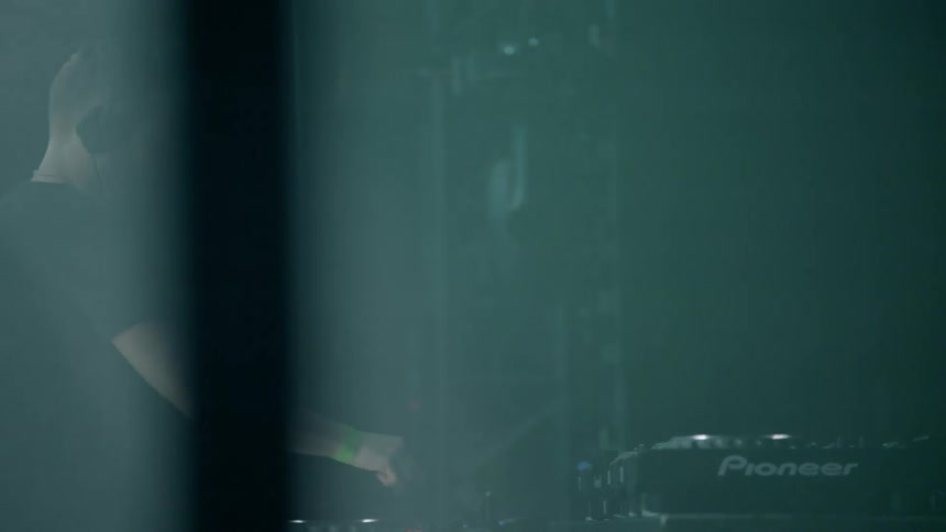 Man wearing headphones bounces up and down behind music equipment