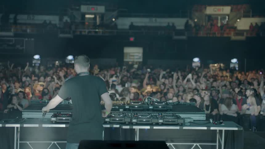A dj is interacting and dancing with the crowd during a performance