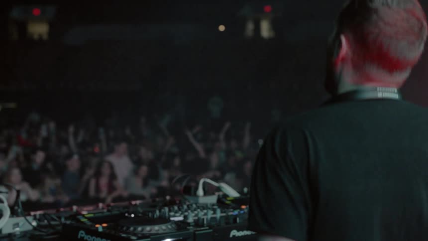A dj dances and jumps in front of his audience