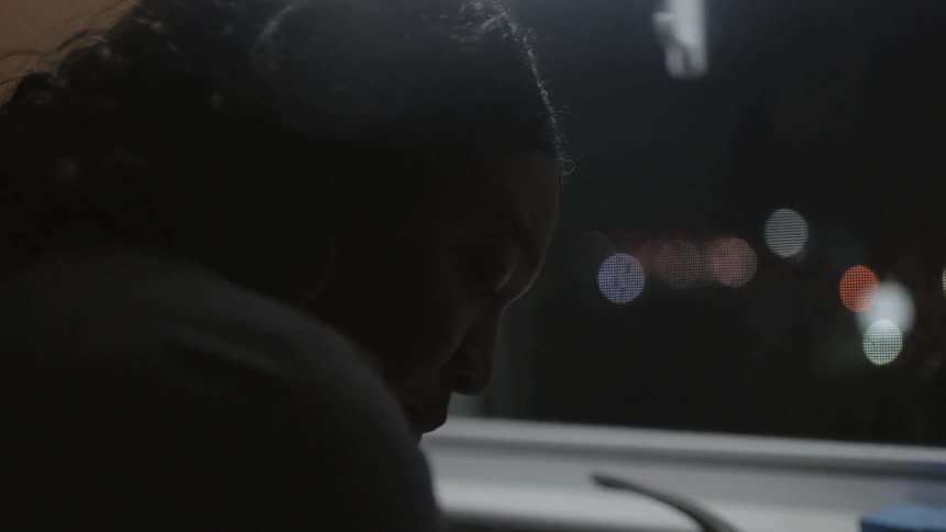 A woman stands next to a kitchen sink at night