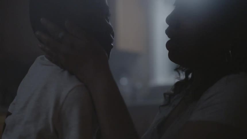 A woman is comforting a young boy in a kitchen at night