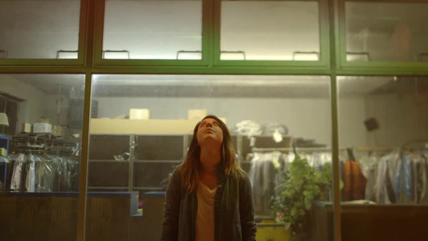 A woman stares upwards in front of a  window