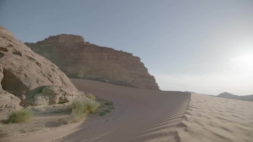 People are crossing a desert on a sunny day