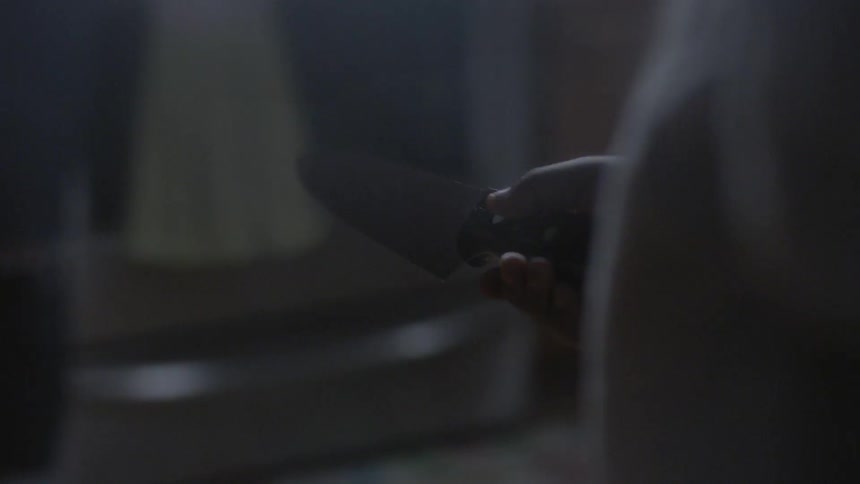 Someone is holding a knife walking through a house