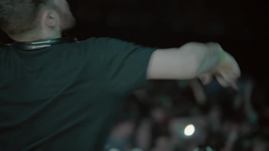 Man with headphones around his neck dances on stage