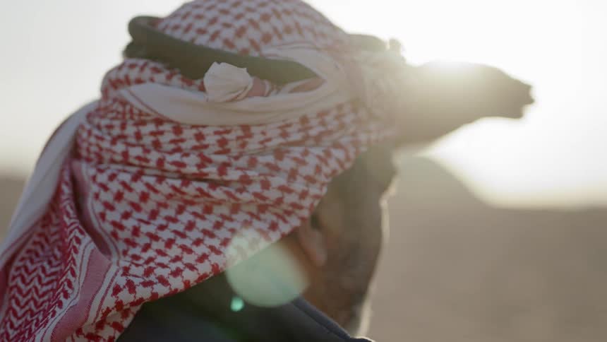 A man wearing a turban shields his face from the sun