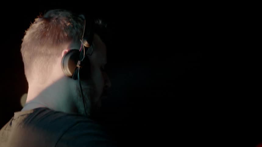 A dj with headphones is playing a concert in front of people