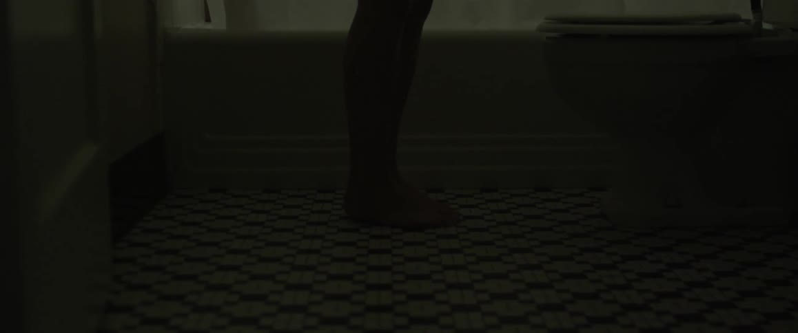 A person stands on bathroom tile near the tub and toilet