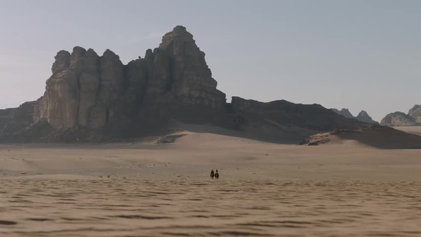 Two people are traveling in the distance of this desert