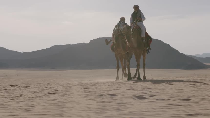 People ride camels in the desert
