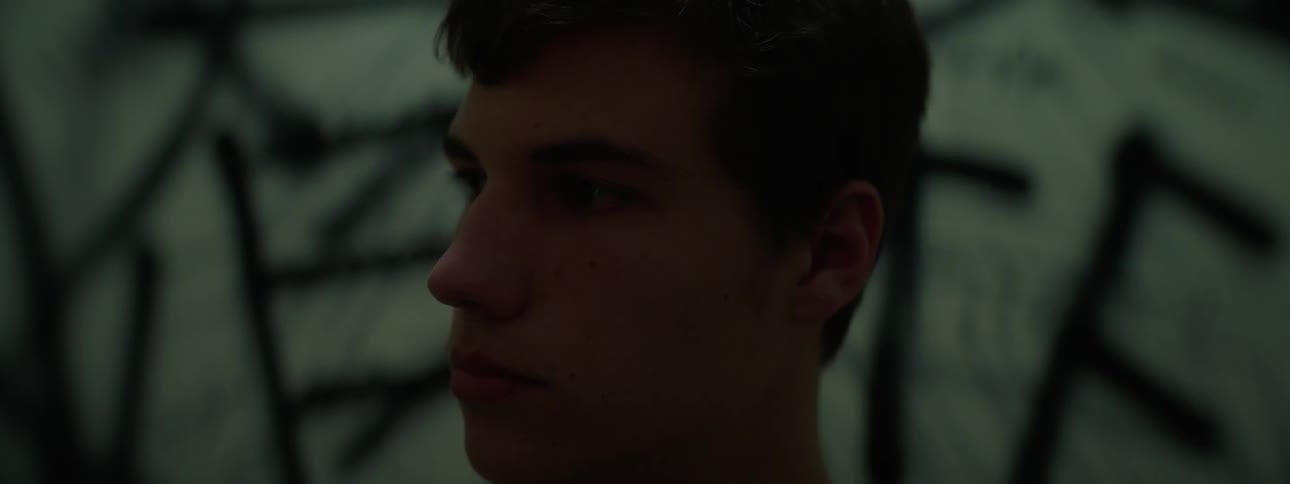 A young man is looking at something off camera and then looks at the camera