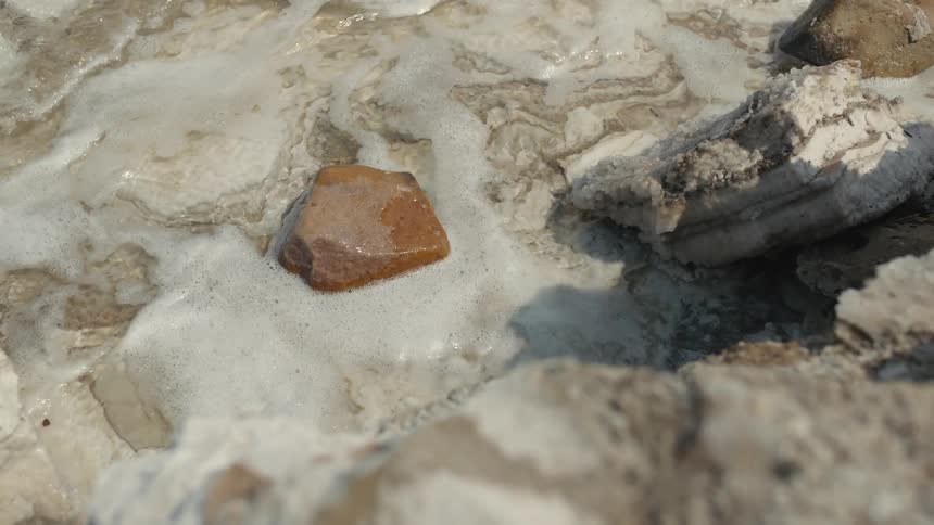 The tide laps a rock during the day