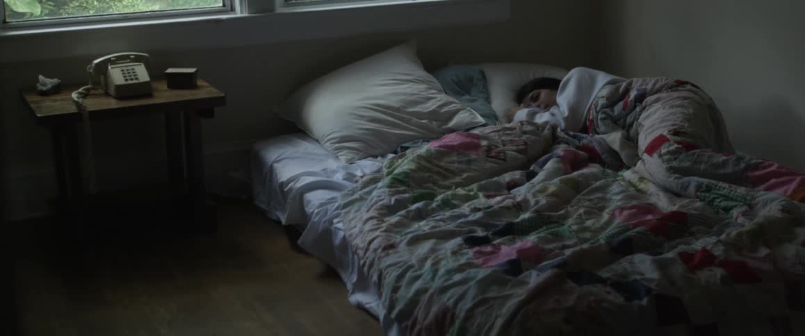 A woman sleeps on a mattress on the floor