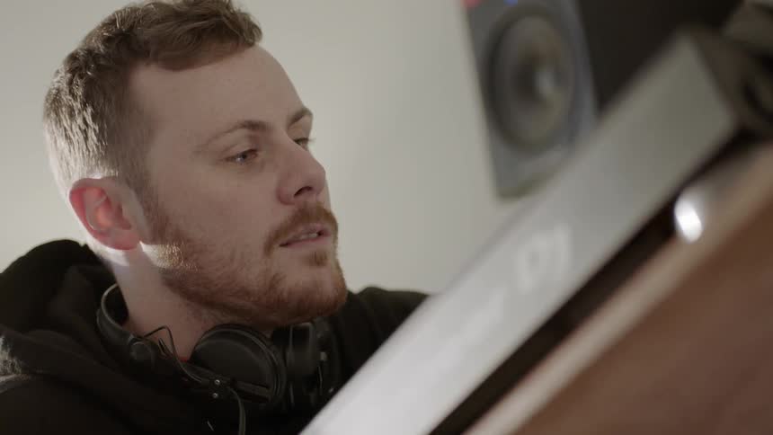 A man with headphones around his neck is using a dj deck