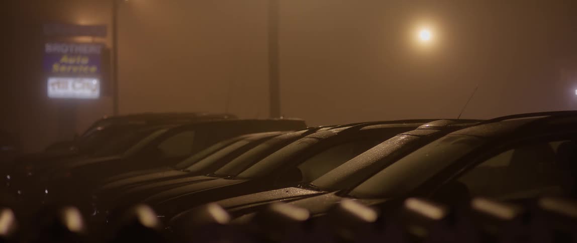 Mist falls on a row of parked vehicles at night