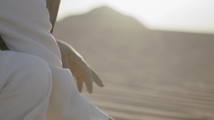 A man is picking up sand from the desert