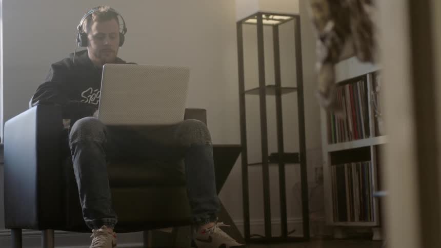 A man wearing headphones works on a laptop