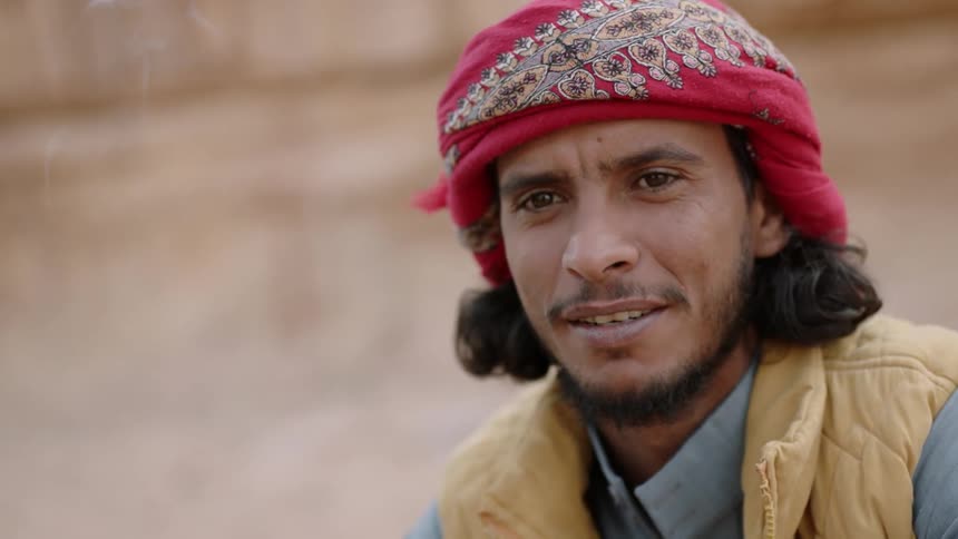 A man smiles as he smokes a cigarette