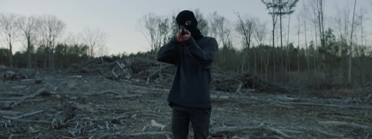 A man wearing a ski mask and holding a rifle is being filmed