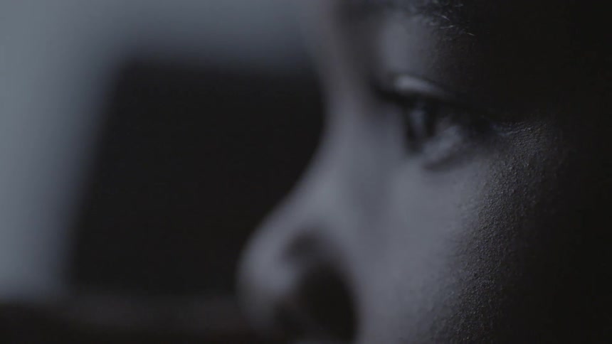 A boy is blinking slowly in a dark room