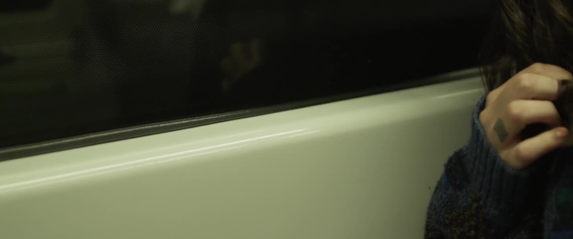 A girl is playing with her hair and looking out the window of a bus