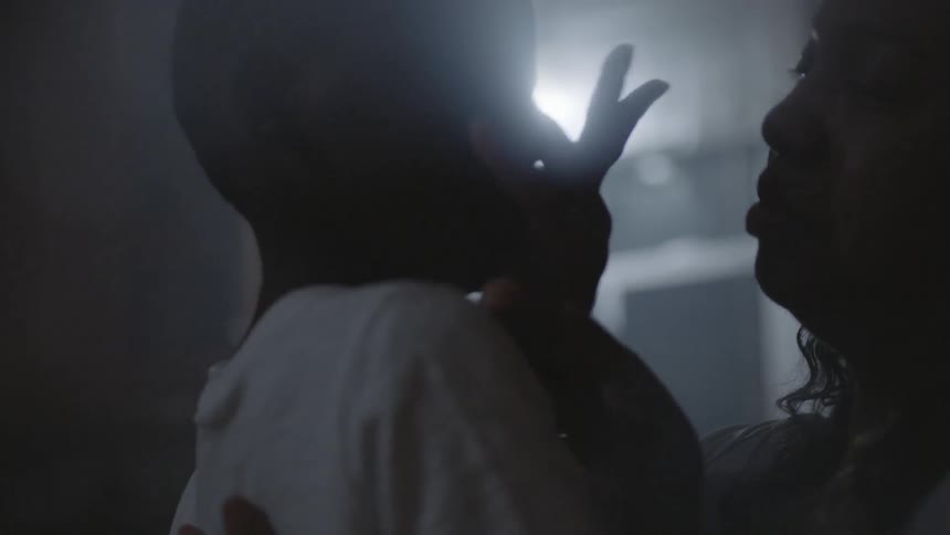 A mother is wiping the face of a young boy