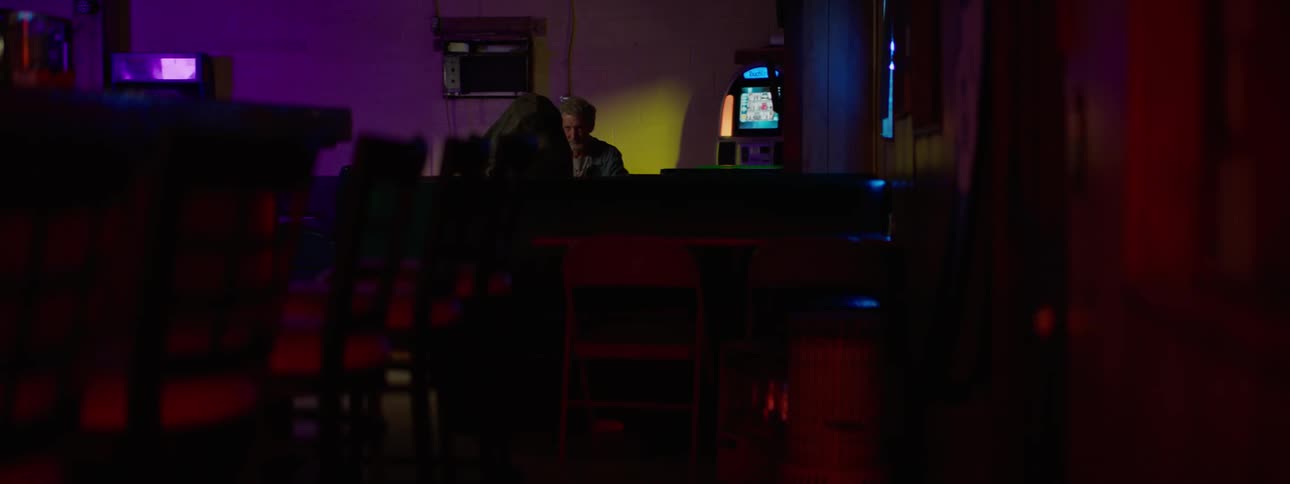 A man is sitting in a dark bar