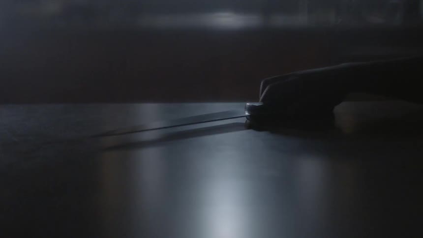 A person grabs a knife sitting on the counter