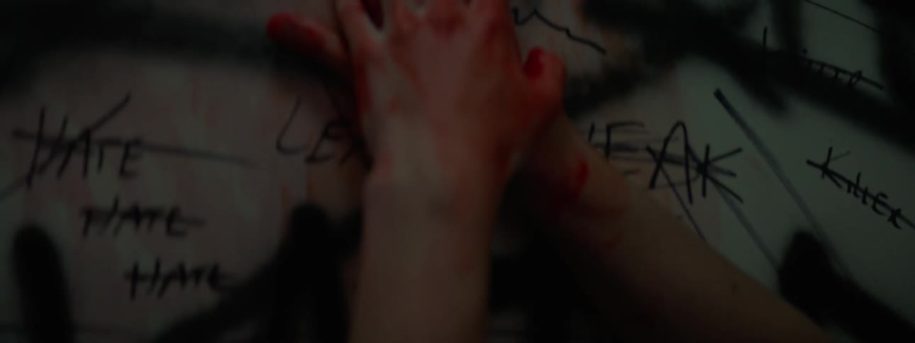 A man wipes his bloody hands on the wall